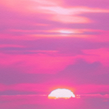 Pink and purple sunset sky with a bright sun near the horizon and a dark band of clouds across the lower middle.